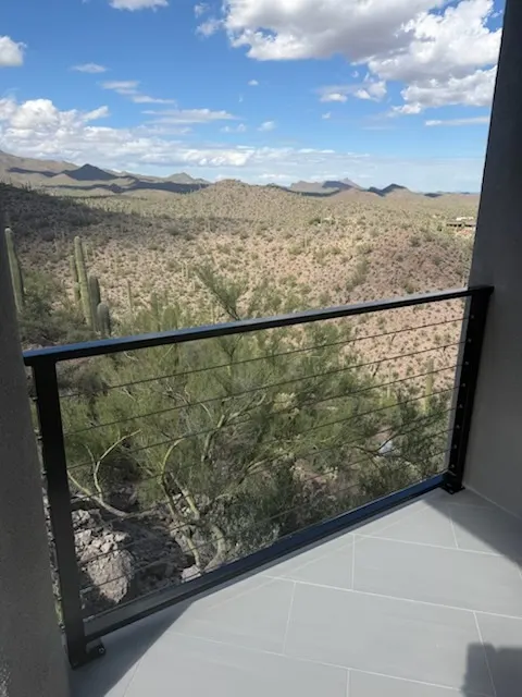 Black steel cable railing on a tiled balcony looking out over saguaros and desert mountains