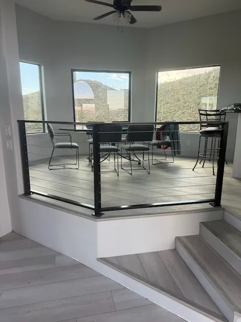 Black steel cable railing around a raised dining area, with saguaro hills out the windows