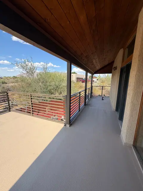 Horizontal steel railing along a covered balcony with a desert view