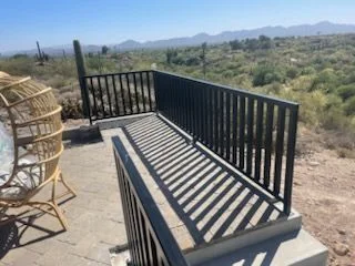 Black steel railing along a raised patio deck looking out over desert and mountains
