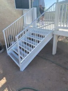 White steel stair with railings on both sides up to a backyard deck