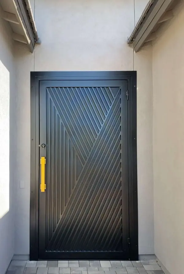 Satin black security door with a diagonal line pattern and a brass pull at a recessed entry