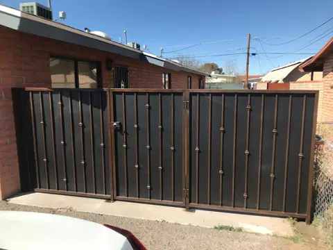 Black steel fence panels with bars and collars beside a brick house