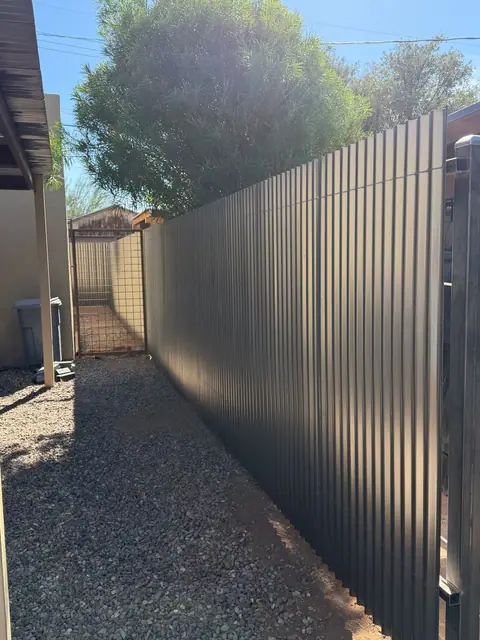 Black steel privacy fence along a gravel side yard