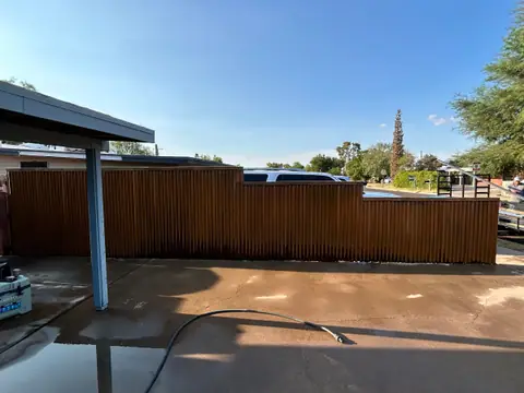 Rusted corrugated steel fence beside a steel carport