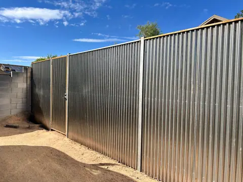 Galvanized corrugated steel privacy fence along a block wall