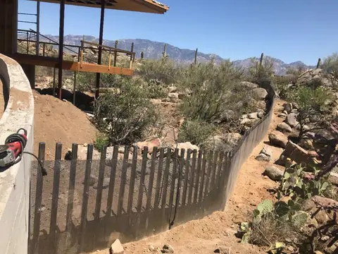 Steel picket fence stepping down a desert hillside with mountains behind