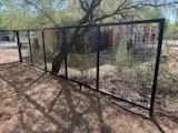 Black steel frame fence with wire mesh panels in a shaded desert yard