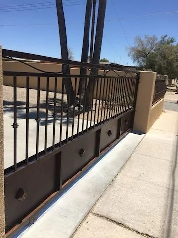 Black steel picket fence with a solid lower panel along a street sidewalk