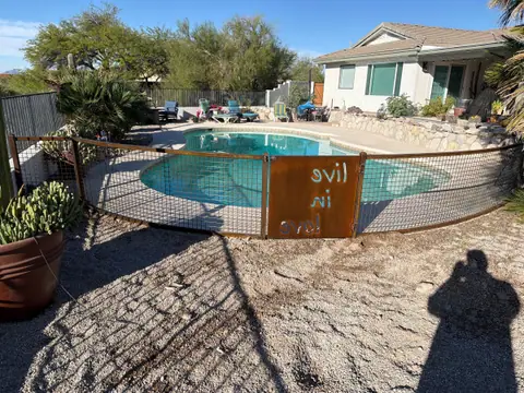 Wire panel pool fence on a steel frame with a rusted cut steel sign panel