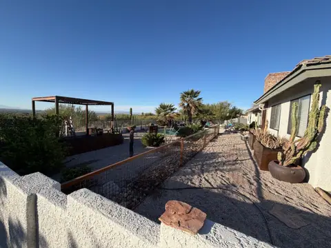 Wire panel fence on steel posts along a desert garden path, with a steel pergola beyond