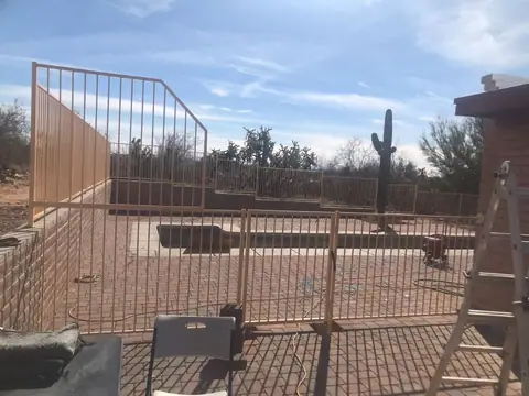 Steel bar fence going up around a backyard on a desert lot with a saguaro behind