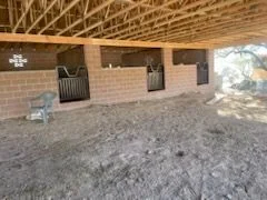 Steel stall gates set in block stalls under a wood truss barn roof