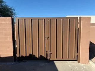 Brown ribbed steel double gate with a center latch between block pillars