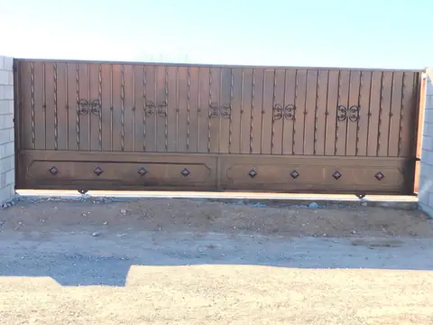 Wide brown drive gate with butterfly cutouts above a diamond panel base