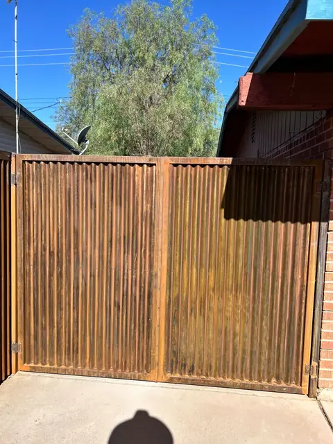 Double gate in rusted corrugated steel at the end of a driveway