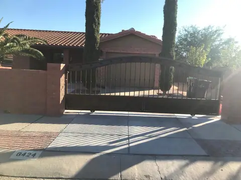 Arched bar rolling gate across a driveway between brick walls