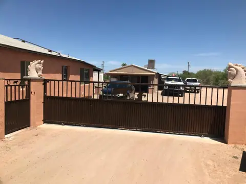 Brown rolling drive gate between block pillars topped with horse head statues