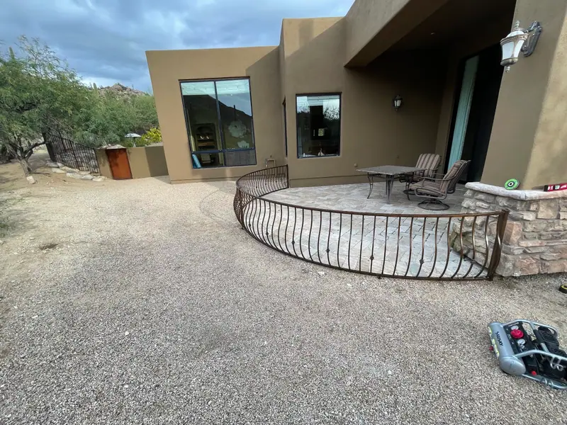 Curved black steel railing following the edge of a flagstone patio at a desert home