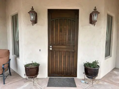 Bronze security door with an arched bar pattern between two wall lanterns