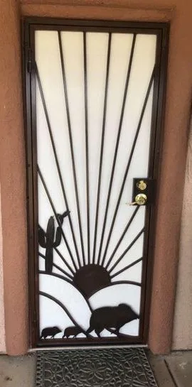 Dark bronze security door with a cut steel desert sunset, a saguaro and a family of javelinas over a white panel