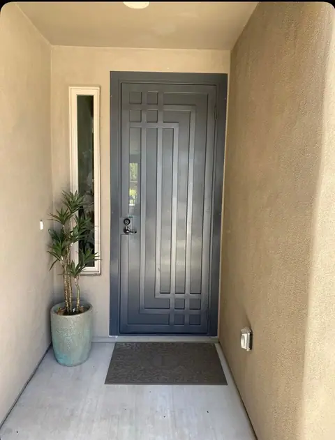 Gray security door with a geometric line pattern at a recessed entry with a sidelight