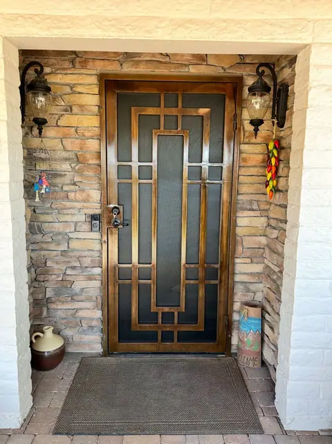 Security door with a geometric pattern in bronze set in a stacked stone entry