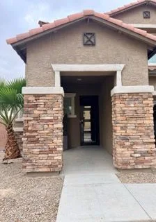 Covered porch entry with stacked stone columns and a black door at the back of the recess