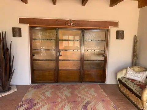 Three panel security screen doors in bronze across a Santa Fe style entry with wood vigas