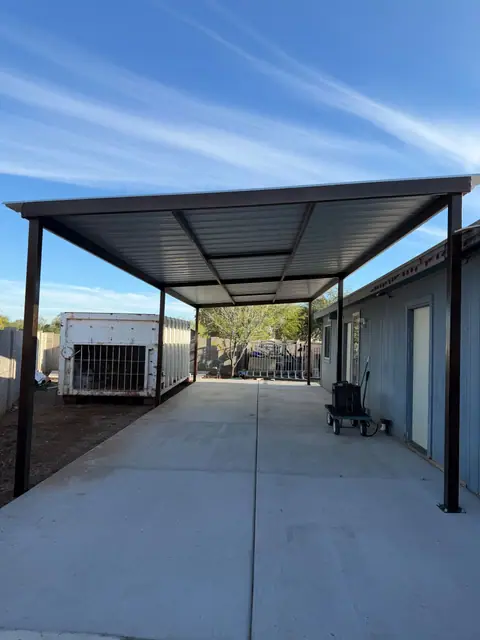 Long steel carport with a metal roof beside a house