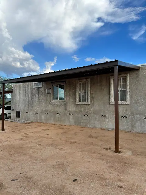 Steel porch cover with a metal roof along a block house